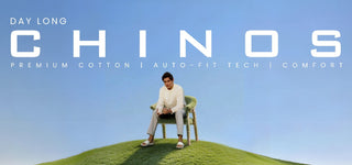 Person sitting on a chair on a grassy hill with 'Day Long Chinos' branding above.