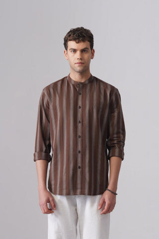 Man wearing a brown striped shirt and white pants on a gray background