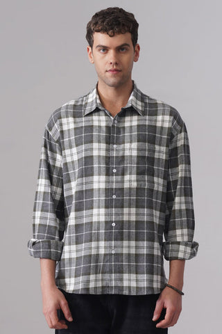 Man wearing a plaid shirt and black pants on a gray background