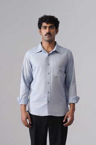 Man wearing a light blue shirt and black pants on a gray background