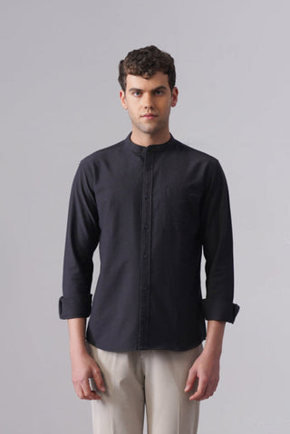 Man wearing a black long-sleeve shirt and beige pants on a gray background